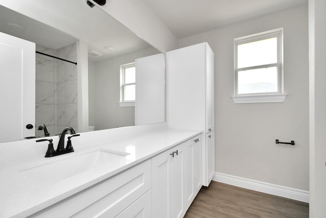 full bathroom with wood finished floors, walk in shower, vanity, and baseboards