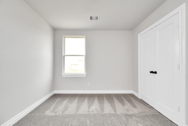 empty room with carpet, visible vents, and baseboards