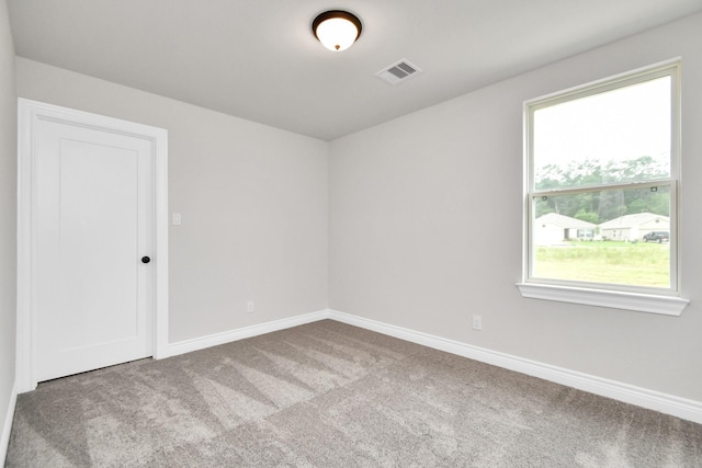 unfurnished room with carpet floors, visible vents, and baseboards