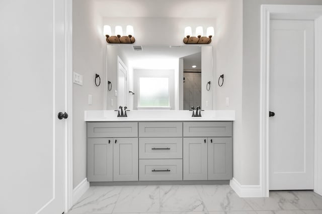 full bath with double vanity, marble finish floor, baseboards, and visible vents