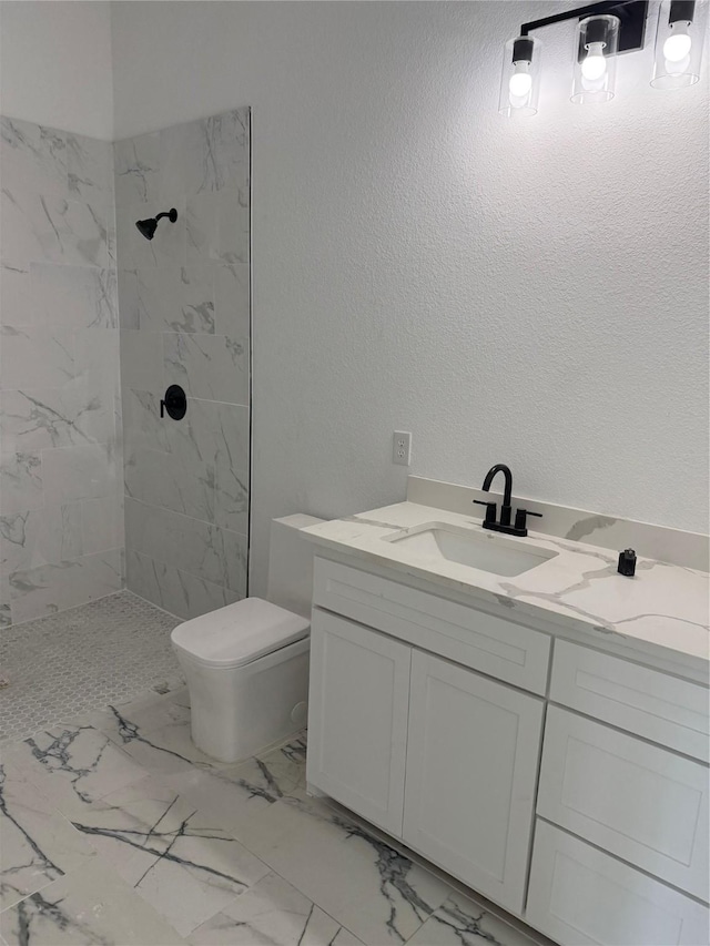 bathroom with vanity, toilet, and a tile shower