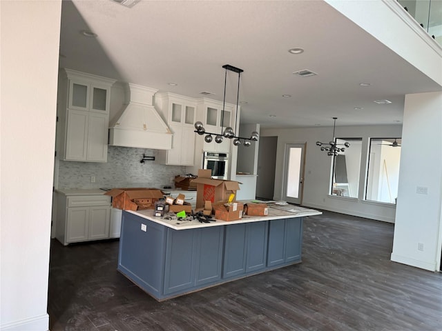 kitchen featuring white cabinetry, hanging light fixtures, a spacious island, and custom exhaust hood