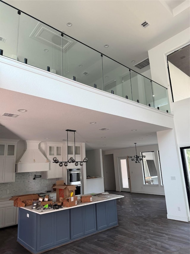 kitchen with pendant lighting, tasteful backsplash, white cabinetry, and custom exhaust hood