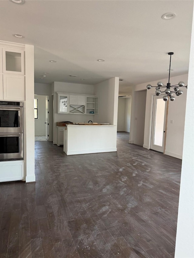 unfurnished living room featuring a notable chandelier and dark hardwood / wood-style floors