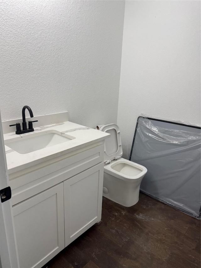 bathroom with hardwood / wood-style floors, vanity, and toilet