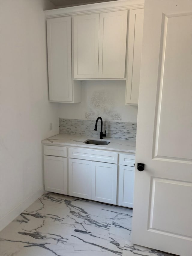 kitchen with light stone counters, sink, and white cabinets