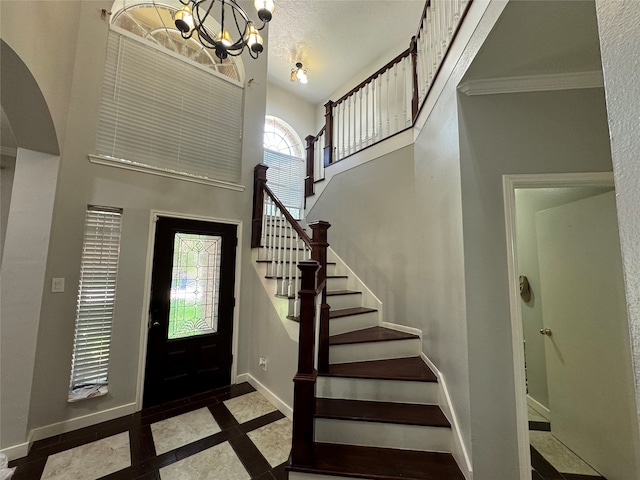 entrance foyer with a high ceiling, plenty of natural light, and an inviting chandelier