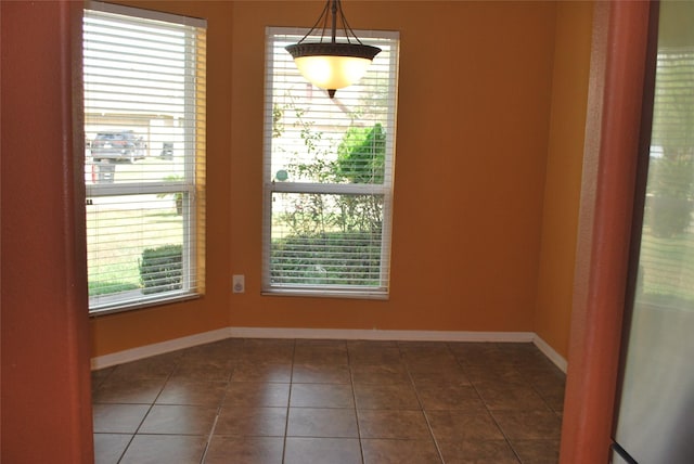 unfurnished room with dark tile patterned flooring and plenty of natural light