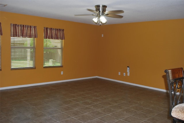 unfurnished room with ceiling fan and dark tile patterned floors