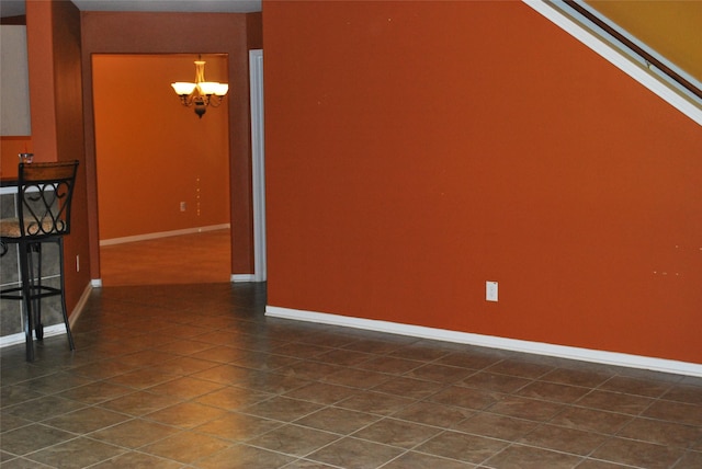 tiled spare room featuring a notable chandelier