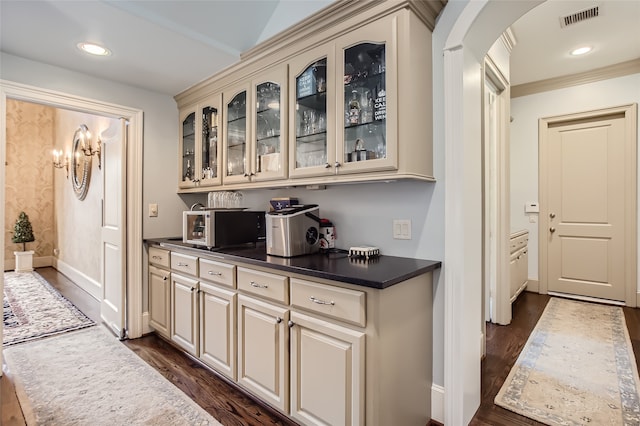 bar with dark hardwood / wood-style floors and cream cabinetry