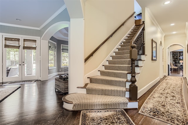 stairs with crown molding, wood-type flooring, and french doors