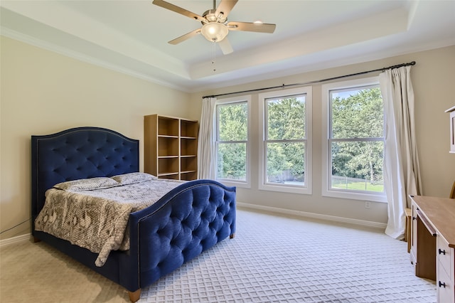 carpeted bedroom with a raised ceiling, ceiling fan, and ornamental molding