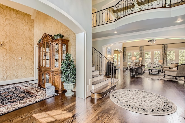 25002 Falling Water Estates Ln, Katy, TX 77494 - entrance foyer featuring arched walkways, a high ceiling, wallpapered walls, wood finished floors, and stairway