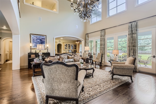 living room featuring dark hardwood / wood-style floors, ceiling fan with notable chandelier, and a towering ceiling