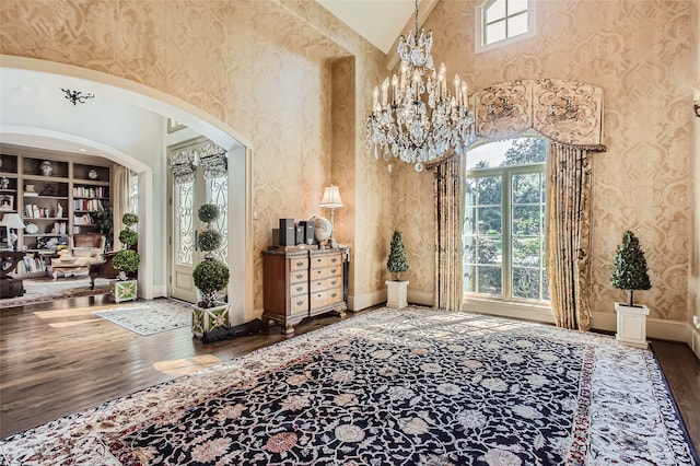 foyer with a wealth of natural light, hardwood / wood-style floors, an inviting chandelier, and a high ceiling