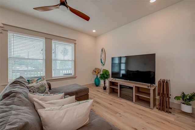 living room with light wood-type flooring, ceiling fan, and a wealth of natural light