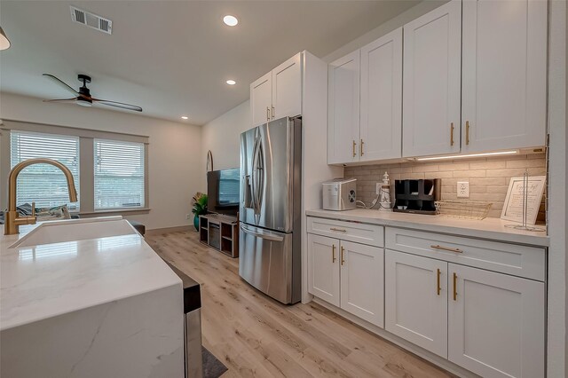 kitchen featuring stainless steel fridge, sink, ceiling fan, white cabinets, and light hardwood / wood-style floors