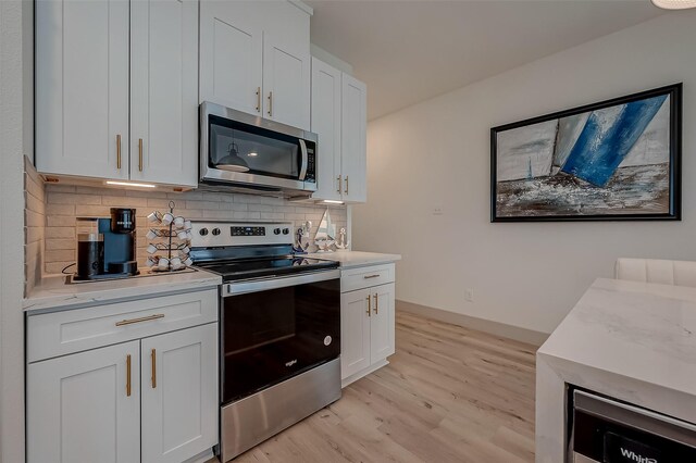 kitchen with appliances with stainless steel finishes, white cabinetry, tasteful backsplash, and light hardwood / wood-style floors