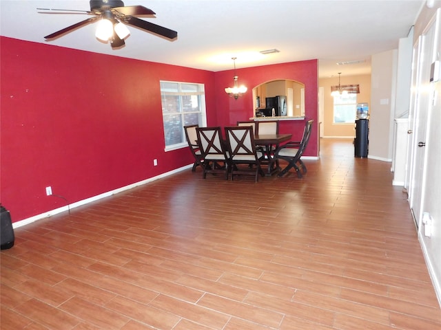 dining room with wood-type flooring and ceiling fan with notable chandelier