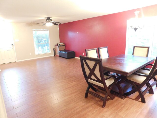 dining area with light wood-type flooring and ceiling fan with notable chandelier