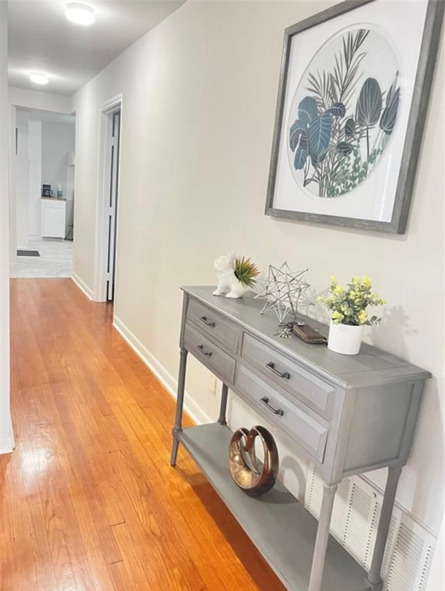 hall with light wood-type flooring and baseboards