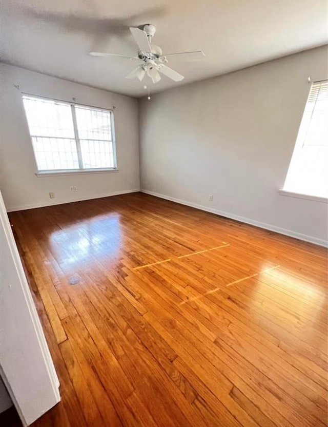 spare room with plenty of natural light, a ceiling fan, baseboards, and wood finished floors