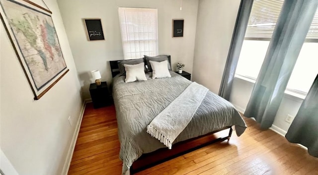 bedroom featuring baseboards, wood finished floors, and multiple windows