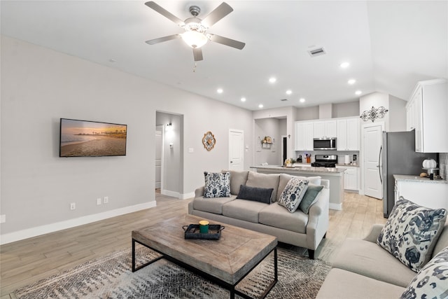 living room with ceiling fan and light hardwood / wood-style flooring