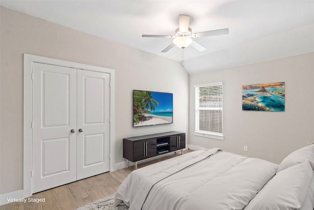 bedroom featuring a closet, light wood-type flooring, vaulted ceiling, and ceiling fan