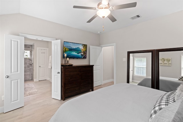 bedroom featuring light hardwood / wood-style floors, ceiling fan, vaulted ceiling, and connected bathroom