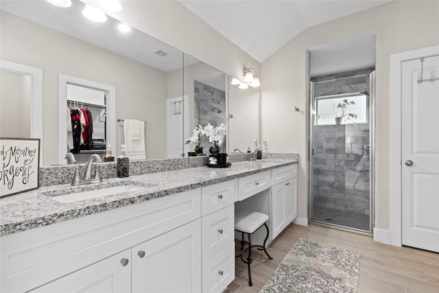 bathroom with vanity, hardwood / wood-style flooring, vaulted ceiling, and a shower with shower door