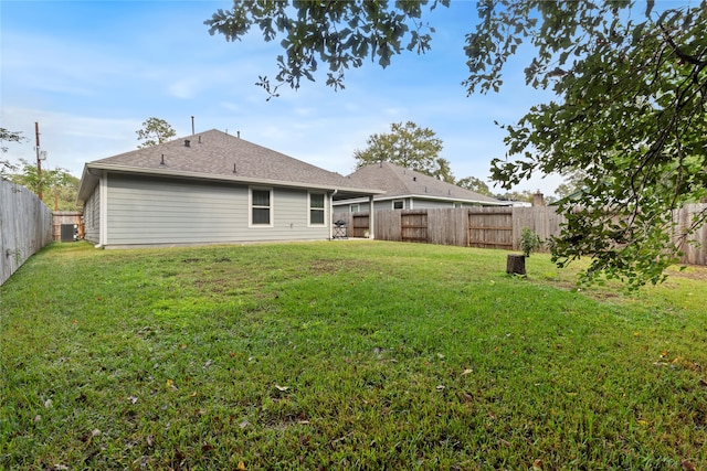 rear view of house with central AC and a yard