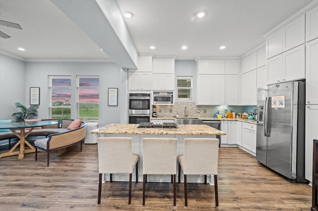 kitchen with a center island, wood-type flooring, white cabinets, sink, and stainless steel appliances