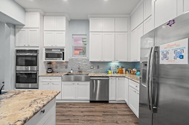 kitchen with white cabinets, appliances with stainless steel finishes, tasteful backsplash, and sink