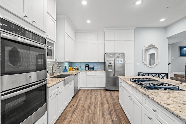 kitchen with hardwood / wood-style floors, light stone countertops, white cabinetry, sink, and stainless steel appliances