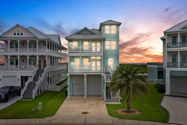 raised beach house featuring a balcony, a garage, and a yard