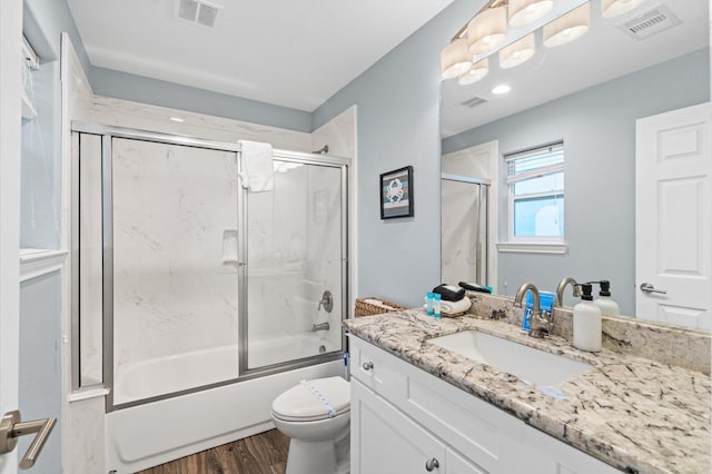 full bathroom with hardwood / wood-style flooring, toilet, enclosed tub / shower combo, and vanity