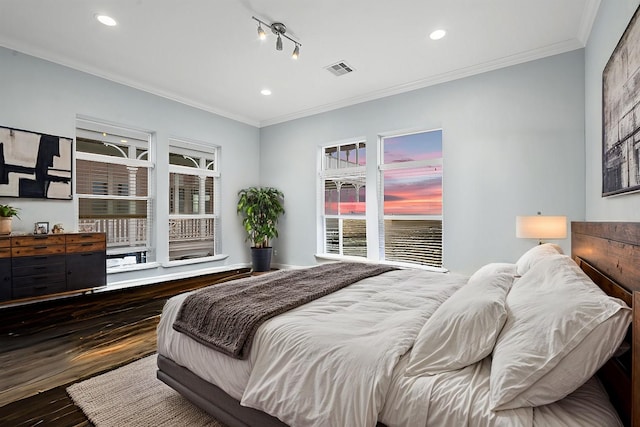 bedroom featuring crown molding, track lighting, and dark hardwood / wood-style flooring