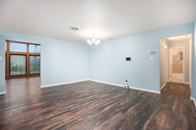 spare room with dark hardwood / wood-style floors and a chandelier