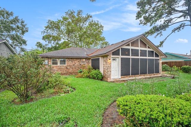 back of property with a yard and a sunroom