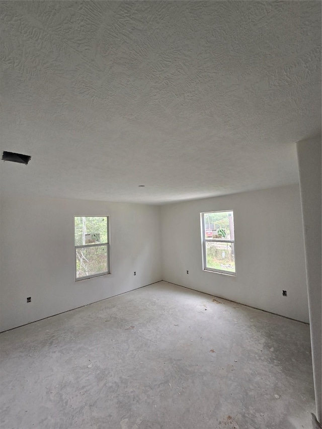 empty room with a wealth of natural light and a textured ceiling