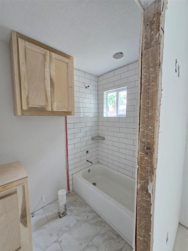 full bathroom featuring marble finish floor and a textured ceiling