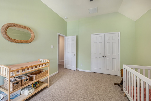 bedroom with vaulted ceiling, a crib, light colored carpet, and a closet