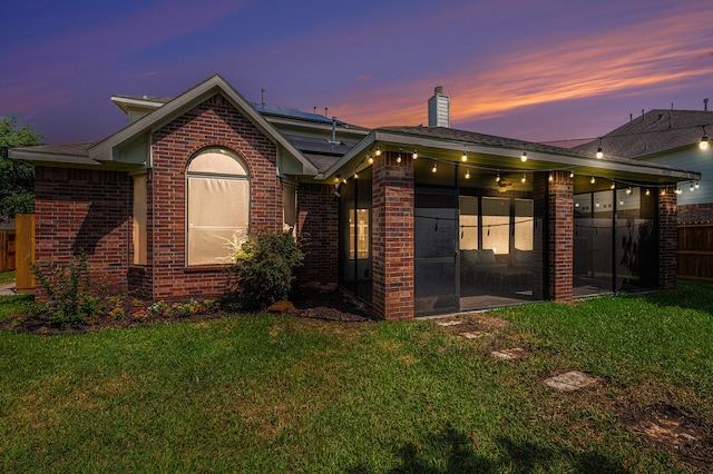 back house at dusk with a lawn