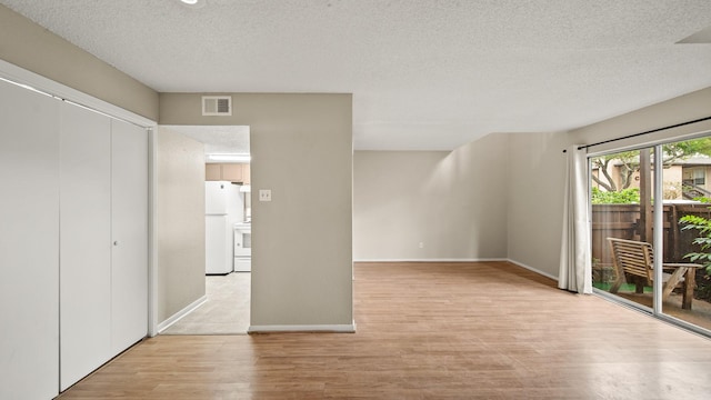 interior space featuring baseboards, visible vents, light wood-style floors, and a textured ceiling
