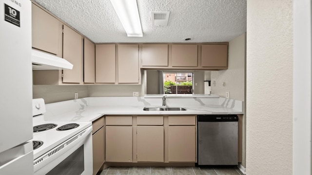 kitchen with white appliances, a textured wall, under cabinet range hood, a textured ceiling, and a sink