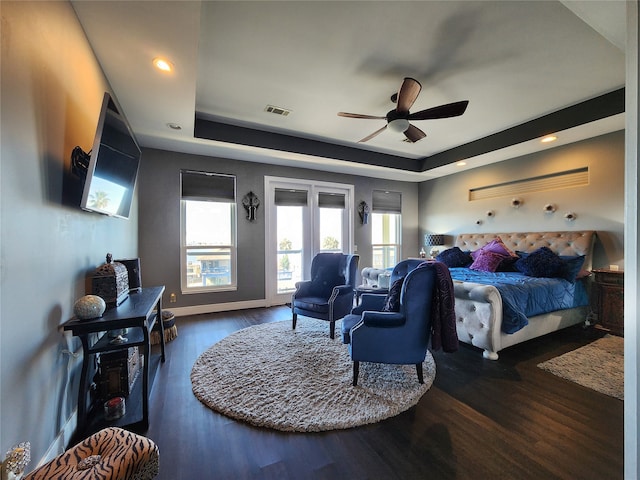 bedroom with ceiling fan, a raised ceiling, dark wood-type flooring, and access to outside