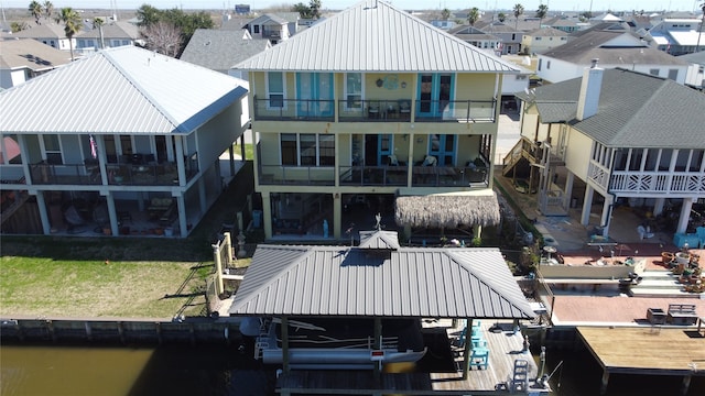 back of house featuring a yard, a balcony, and a water view