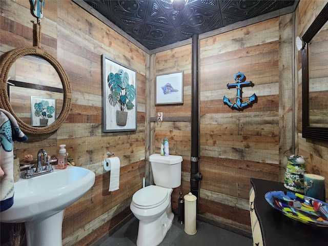 bathroom with wood walls, toilet, and concrete flooring